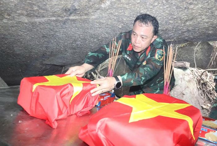 Đại tá Trần Hữu Ích bên các hài cốt liệt sĩ vừa được tìm thấy ở hang Đá Sập.