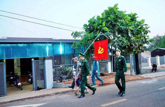 Già làng, Người có uy tín Rơ Mah Blơih phấn khởi cùng Bộ đội Biên phòng treo cờ Đảng trước nhà. Ảnh: Ngọc Thu