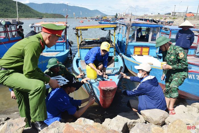 Lực lượng biên phòng, công an, đoàn viên thanh niên hỗ trợ ngư dân Hải Ninh sơn sửa số hiệu tàu thuyền.
