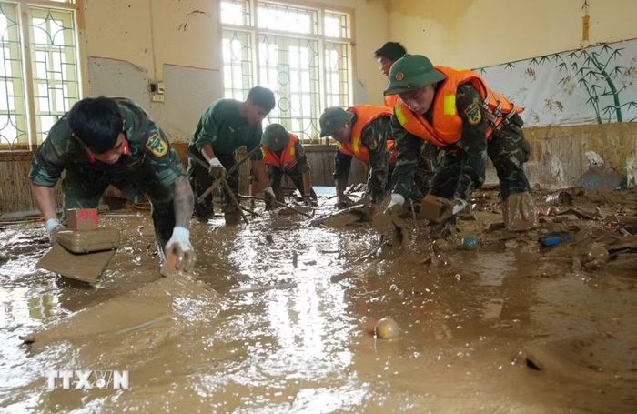 Các chiến sỹ lội bùn dọn dẹp tại vùng lũ Mường Than. (Ảnh: Nguyễn Oanh/TTXVN)