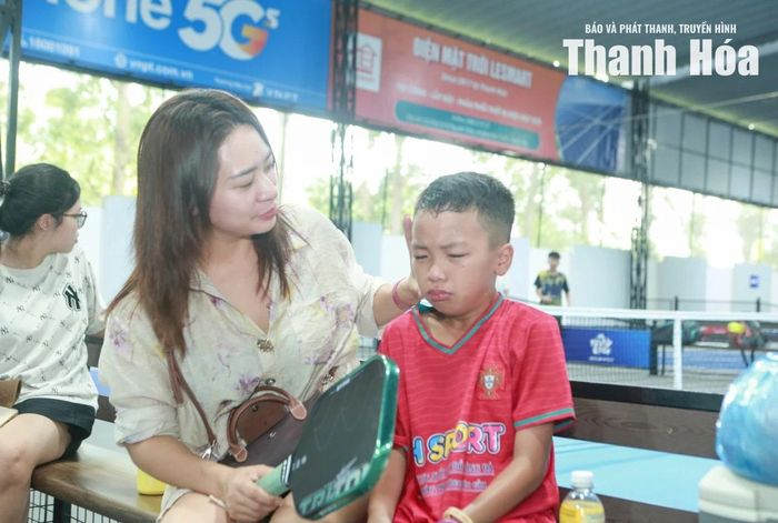 Chị Lê Bảo Yến cho biết: “Công tác tổ chức giải năm nay rất bài bản, quy mô và chuyên nghiệp. Điều tôi ấn tượng nhất chính là không khí trên khán đài, quá cuồng nhiệt và văn minh! Tiếng hò reo, vỗ tay của khán giả chính là liều thuốc tinh thần giúp các cháu thi đấu thăng hoa. Con trai tôi có buồn vì kết quả không đạt được như kỳ vọng nên tôi và gia đình luôn khích lệ từ đầu đến cuối. Với tư cách là phụ huynh, chúng tôi luôn đồng hành, tạo mọi điều kiện tốt nhất để các con theo đuổi đam mê thể thao”. (Trong ảnh: Chị Yến động viên con trai Hà Huy Bách sau trận đấu).