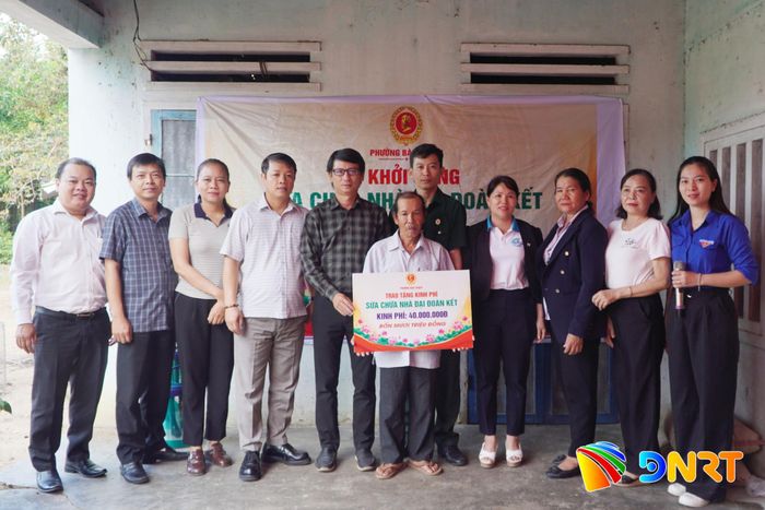 Đại diện lãnh đạo địa phương trao bảng tượng trưng kinh phí sửa chữa nhà đại đoàn kết cho ông Phạm Được. Ảnh: PHAN VINH
