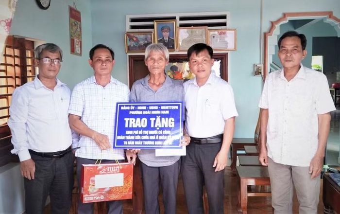 Ông Nguyễn Xuân Tú - Bí thư Đảng ủy phường Hoài Nhơn Nam (thứ 2 từ phải sang) trao hỗ trợ kinh phí sửa chữa nhà cho thương binh Đinh Xuân Tôi (khu phố Hoài Xuân). Ảnh: ĐVCC