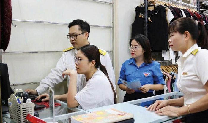 Cán bộ thuế hướng dẫn hộ kinh doanh ghi chép sổ sách và kê khai thuế theo quy định mới. Ảnh: Đức Thanh