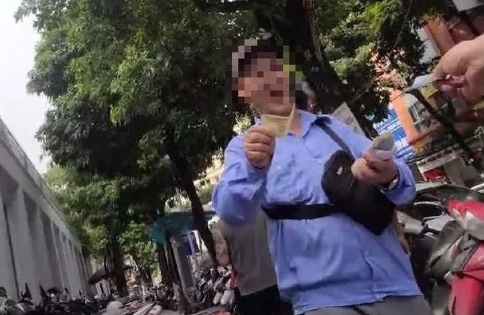 Nhân viên Lê Đình L, thu tiền mặt tại bãi xe thanh toán phí qua mã QR. Ảnh: Đức Tuấn