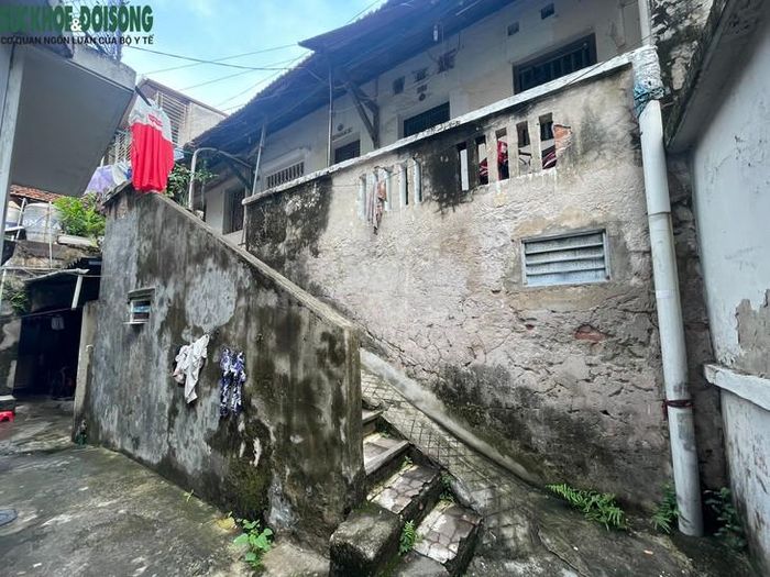 Nhiều mảng tường đã bong tróc lớp vữa, để lộ những viên gạch đỏ cũ kỹ. Rêu xanh phủ kín chân tường, bám lên cầu thang dẫn lên tầng 2 dãy nhà. Ảnh: Đức Phúc
