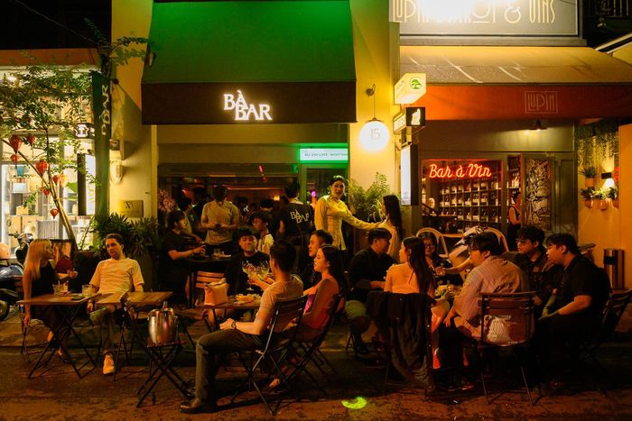 Tiếng vọng cổ vang lên trên nền house music. Sau quầy bar, bartender lắc bình shaker cho ly cocktail lấy cảm hứng từ canh chua, trong khi nhân viên mặc áo bà ba len qua những chiếc bàn chật kín khách. Những chi tiết tưởng chừng đối lập tạo nên một không gian nightlife mang đậm hơi thở Việt Nam đương đại tại BÀ BAR - một quán bar nằm trên đường Nguyễn Cừ (phường An Khánh, TP.HCM).