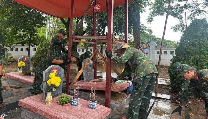 Cán bộ, chiến sĩ Bộ Chỉ huy quân sự tỉnh Điện Biên dùng ba-lăng xích nhấc mặt bia trên từng phần mộ.