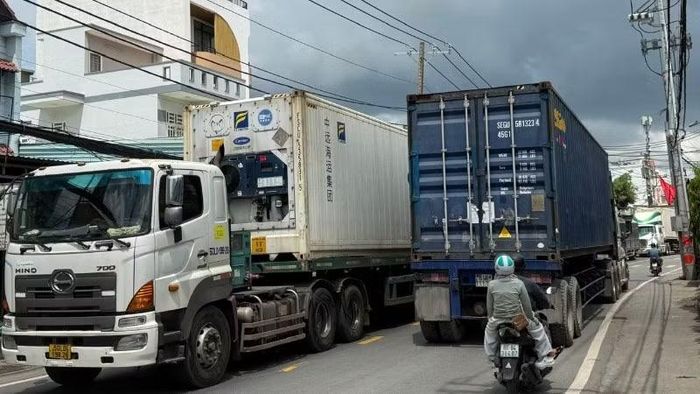Người dân bất an khi di chuyển cùng với dòng xe tải nặng trên tuyến Nguyễn Duy Trinh dẫn vào cảng Phú Hữu. (Ảnh: VÕ LÊ)
