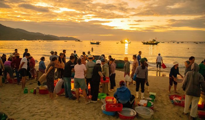  Cảnh họp chợ cá tấp nập, phía xa là những con thuyền vừa trở về sau một đêm vươn khơi. Ảnh: XUÂN QUỲNH 