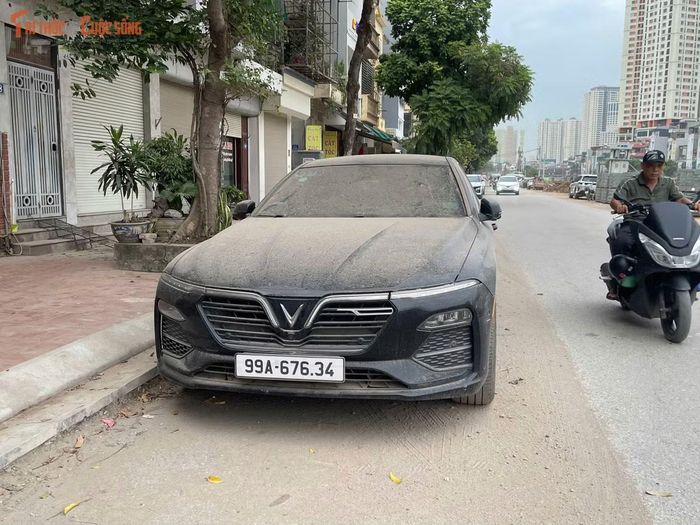 Một chiếc ô tô đỗ ven đường phủ kín bụi sau nhiều giờ nằm cạnh công trường.