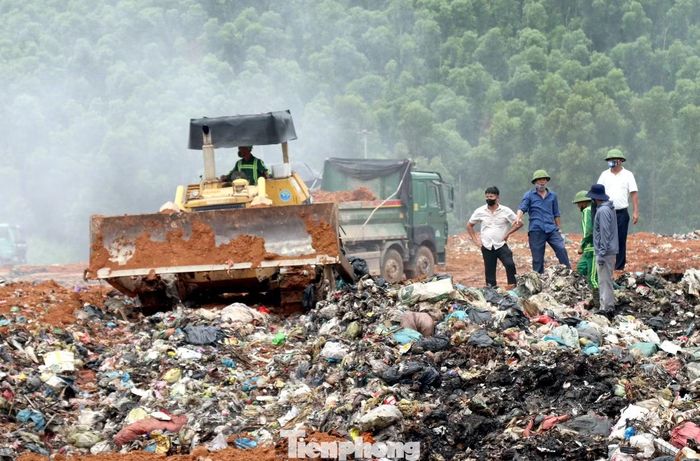 Bên ngoài hiện trường, máy đào và xe ben hoạt động liên tục, vận chuyển đất vào khu vực cháy để phủ kín các lớp rác.