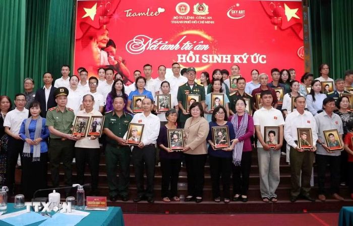Lãnh đạo Thành ủy, Bộ Tư lệnh Thành phố, Công an Thành phố cùng nhóm phục dựng ảnh "Team Lee" trao tặng di ảnh liệt sỹ đã phục dựng cho thân nhân các liệt sỹ. (Ảnh: Xuân Khu/TTXVN)