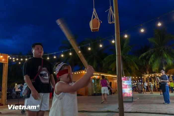 Du khách hào hứng trải nghiệm trò chơi dân gian "đập niêu" ngập tràn tiếng cười. (Ảnh: Thanh Phong/Vietnam+)