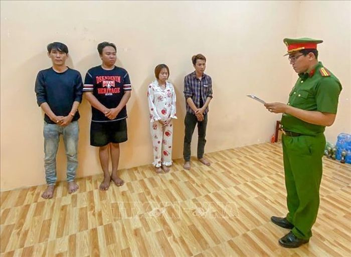 Điều tra viên thi hành Lệnh tạm giam đối với các đối tượng. Ảnh: TTXVN phát