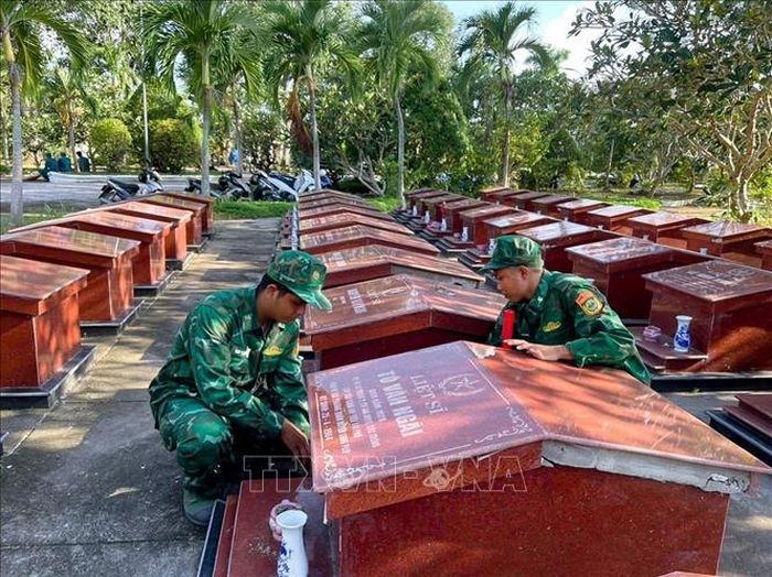 Cán bộ đồn Biên phòng An Thạnh Ba tham gia dọn vệ sinh, chỉnh trang Nghĩa trang Liệt sĩ. Ảnh: TTXVN phát