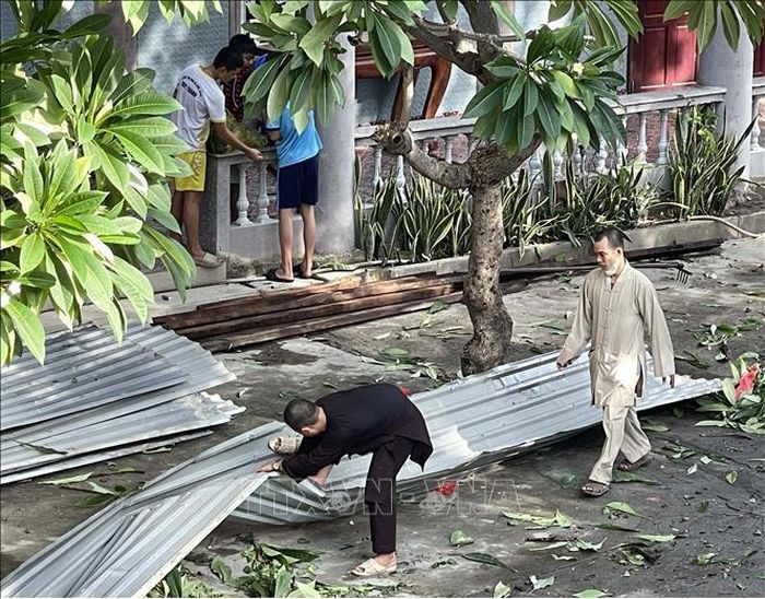 Các sư thầy và tăng ni phật tử dọn dẹp tại chùa Sùng Ân sau giông lốc. Ảnh: Công Thử/TTXVN