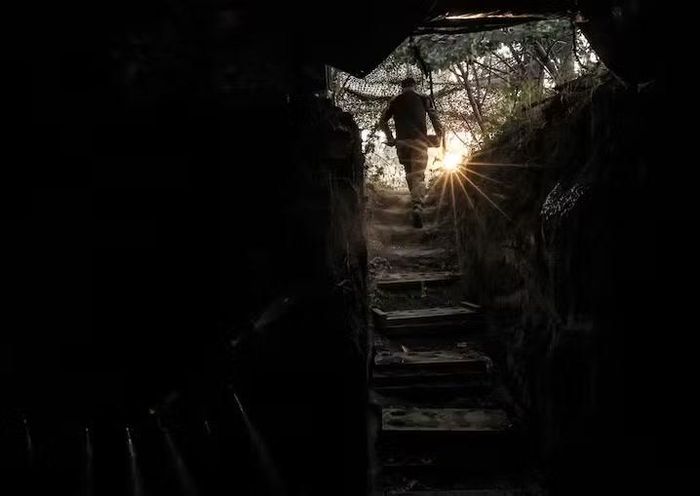 Một binh sĩ thuộc lữ đoàn của Krynitskyi đang đóng quân gần tiền tuyến, cầm theo một quả đạn pháo để bắn vào lực lượng địch. Ảnh: Reuters.