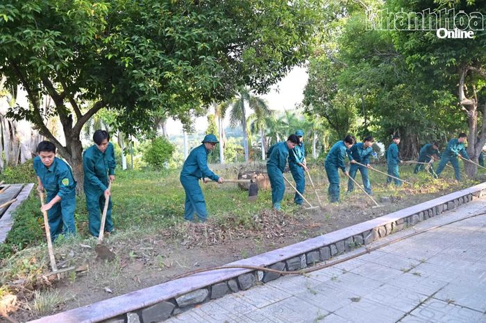 Lực lượng dân quân phường phát quang cỏ dại trong khuôn viên nghĩa trang liệt sĩ.