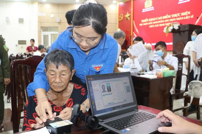 Đoàn viên phường Ninh Hòa hỗ trợ thân nhân liệt sĩ xác thực vân tay trên thiết bị chuyên dụng trước khi lấy mẫu ADN.