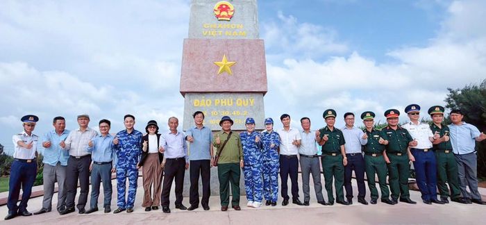 Các đại biểu trong đoàn công tác chụp hình lưu niệm tại Cột cờ chủ quyền Đặc khu Phú Quý