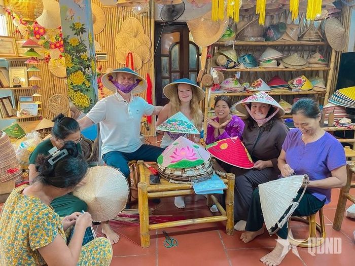 Nghệ nhân Tạ Thu Hương (thứ ba, từ phải sang) chụp hình kỷ niệm cùng du khách tại không gian trải nghiệm của gia đình. Ảnh: NVCC