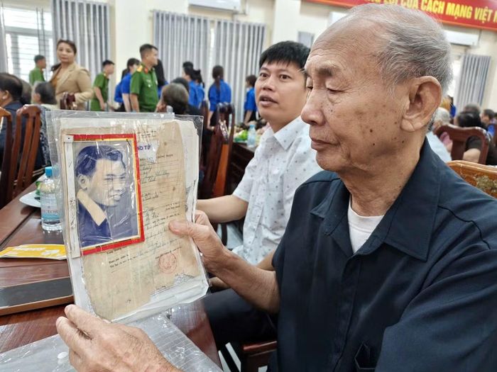 Người thân cầm trên tay di ảnh và giấy báo tử của Anh hùng liệt sĩ.