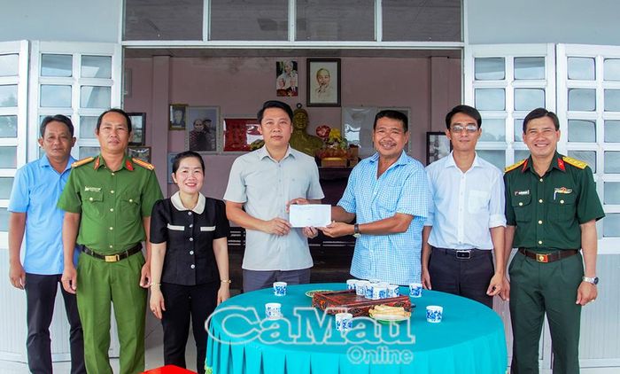 Đồng chí Trần Minh Đẳng, Phó Bí thư Thường trực Đảng ủy xã Phan Ngọc Hiển (giữa) trao quà cho gia đình Anh hùng Lực lượng vũ trang nhân dân
