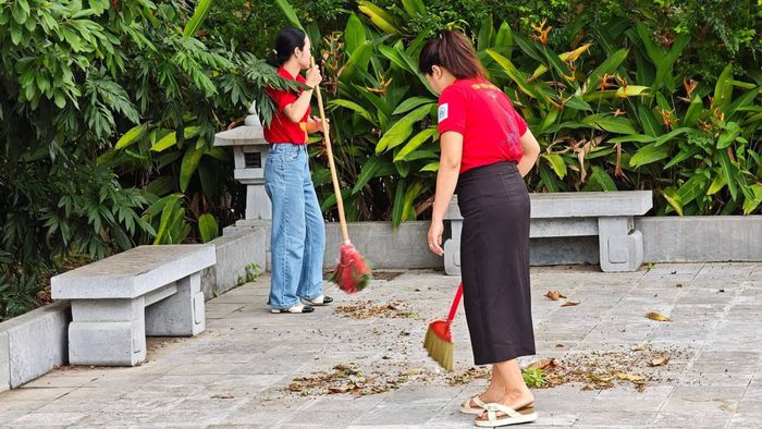 Đoàn viên thanh niên quét dọn, thu gom rác thải trong khuôn viên đài tưởng niệm. Ảnh: PV
