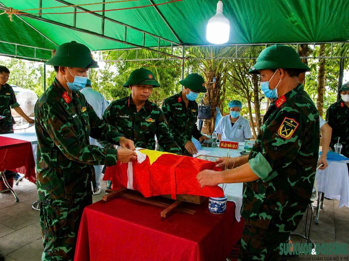 Tiểu sành chứa hài cốt liệt sĩ được phủ Quốc kỳ và đưa đến khu vực lấy mẫu ADN. Mỗi thao tác đều được thực hiện với sự trang nghiêm và tôn kính.
