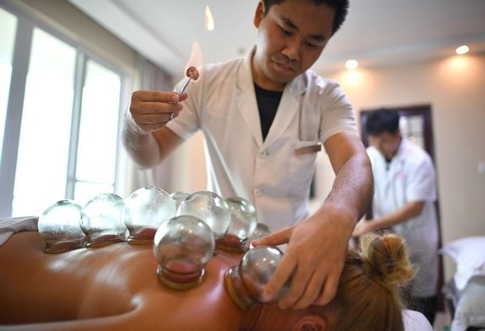  Du khách Nga được nhân viên y tế điều trị bằng y học cổ truyền tại Viện Điều dưỡng Y học Cổ truyền Quốc tế Hữu nghị Sanya, tỉnh Hải Nam, Trung Quốc, hồi tháng 6. Ảnh: Xinhua. 