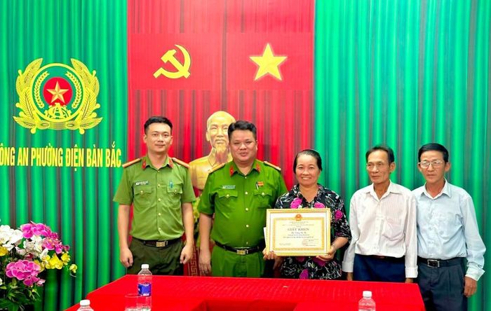 Công an phường Điện Bàn Bắc trao Giấy khen cho bà Thọ.