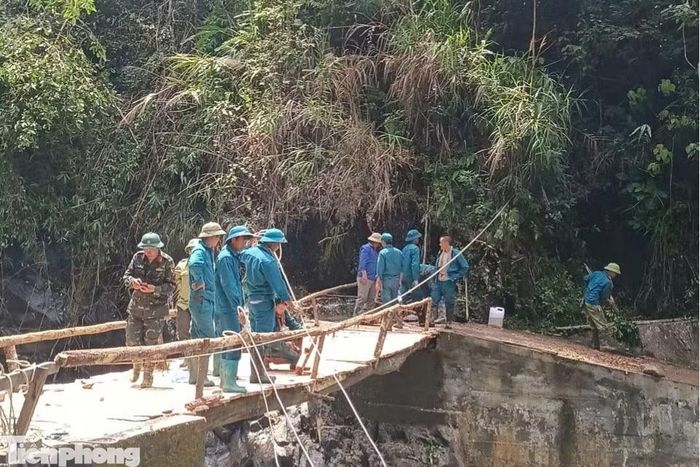 Trước đó, hai cây cầu trên tuyến từ thôn Tà Dông vào khu dân cư Nả Háng đã bị lũ cuốn trôi, khiến khu vực bị chia cắt nhiều ngày (ảnh trên). Để dựng lại cầu tạm, cán bộ, chiến sĩ cùng các lực lượng hỗ trợ đã vượt dòng nước xiết, vận chuyển vật liệu và trực tiếp thi công trong điều kiện hết sức nguy hiểm.
