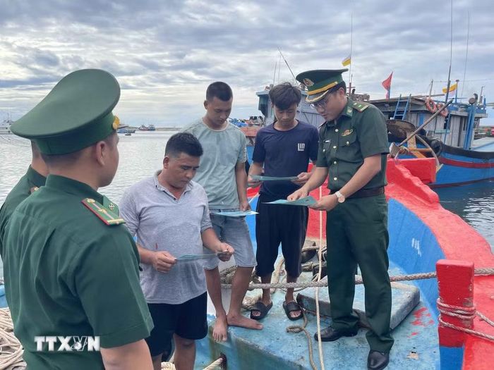 Thiếu tá Mai Văn Tuấn, Chính trị viên phó Đồn Biên phòng Lý Sơn (bên phải) trao đổi với chủ tàu và các thuyền viên về chống khai thác thủy sản bất hợp pháp trước mỗi chuyến tàu ra khơi. (Ảnh: Kha Phạm/TTXVN)