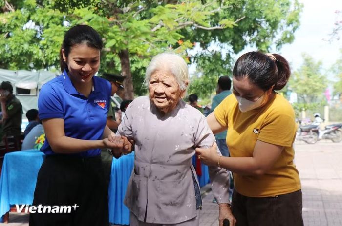 Bà Phạm Thị Ngoạn, 94 tuổi, xã Bình Sơn được người thân hỗ trợ đi đến điểm thu nhận mẫu sinh phẩm ADN để mong tìm được anh ruột là liệt sỹ tên Phạm Lâm. (Ảnh: Phạm Cường/Vietnam+)