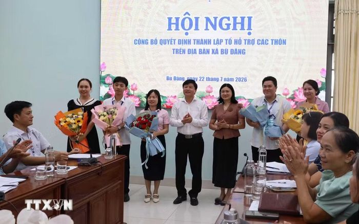 Lãnh đạo Ủy ban nhân dân xã Bù Đăng tặng hoa chúc mừng các thành viên Tổ hỗ trợ nhân dân hoàn tất thủ tục cấp Giấy chứng nhận quyền sử dụng đất lần đầu. (Ảnh: Đậu Tất Thành/TTXVN)
