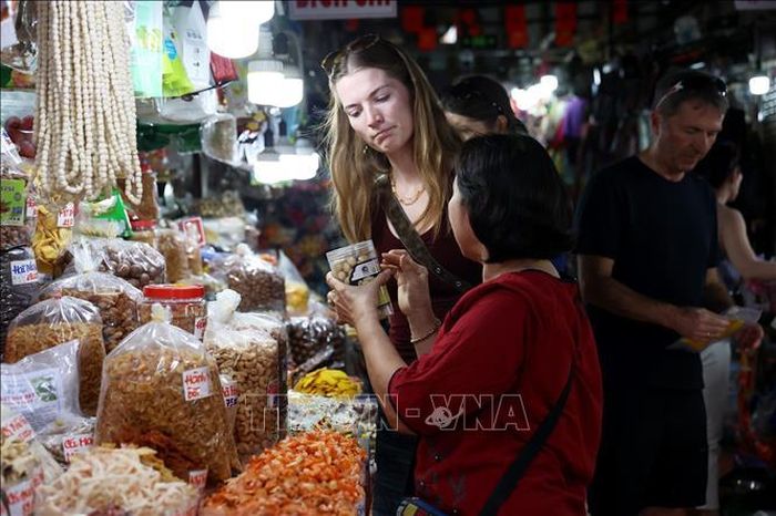 Khách quốc tế tìm hiểu đặc sản ẩm thực Việt trong chợ Tân Định. Ảnh: Hồng Đạt/TTXVN