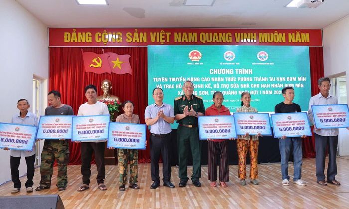 Trung tướng Nguyễn Đức Soát, Chủ tịch Hội Hỗ trợ khắc phục hậu quả bom mìn Việt Nam trao tượng trưng tiền hỗ trợ sinh kế cho các nạn nhân bom mìn của xã Đông Sơn, Quảng Ngãi