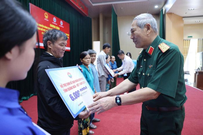 Trung tướng Nguyễn Đức Soát, Chủ tịch Hội Hỗ trợ khắc phục hậu quả bom mìn Việt Nam trao tiền hỗ trợ sinh kế cho các nạn nhân bom mình của xã Sơn Tịnh.