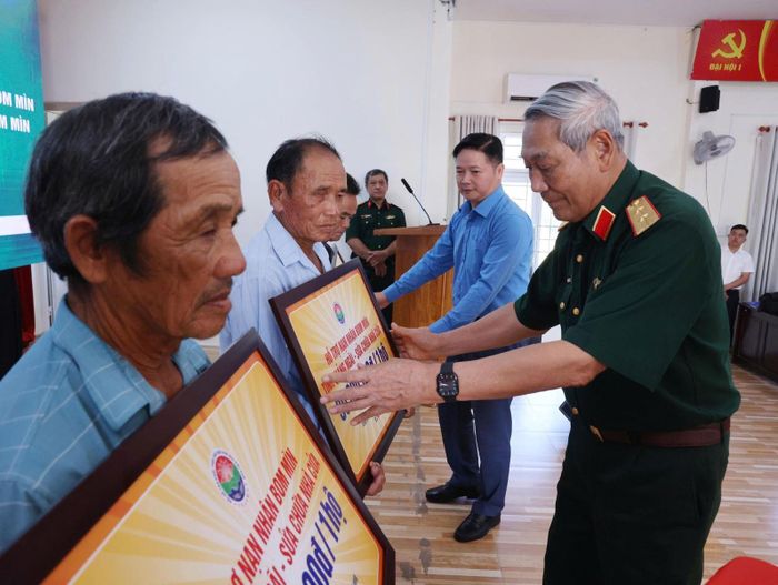 Trung tướng Nguyễn Đức Soát, Chủ tịch Hội Hỗ trợ khắc phục hậu quả bom mìn Việt Nam trao tiền sửa chữa nhà cho các nạn nhân bom mìn của xã Đông Sơn, Quảng Ngãi.