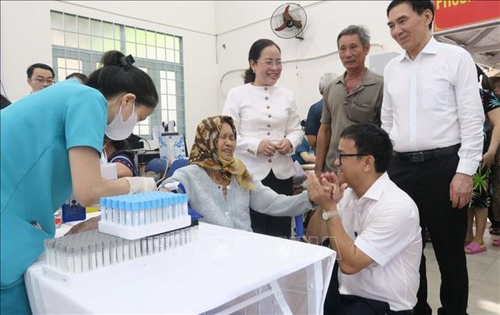Ông Huỳnh Minh Chín (ngồi, bên phải), Phó Giám đốc Sở Y tế Thành phố Hồ Chí Minh, động viên một người cao tuổi tại phường Bình Qưới trong khi lấy máu xét nghiệm.