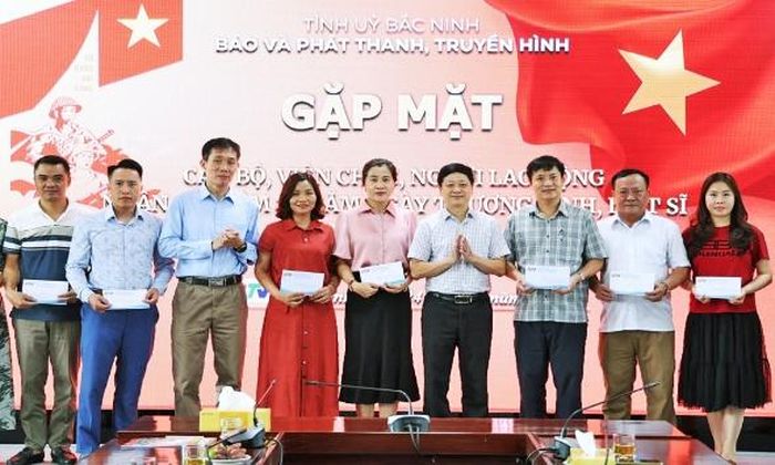  Các đồng chí Phó Giám đốc Báo và Phát thanh, Truyền hình Bắc Ninh: Trần Văn Đức, Nguyễn Ngọc Thái trao quà của cơ quan tới cán bộ, viên chức, người lao động để chuyển đến thân nhân là người có công. 