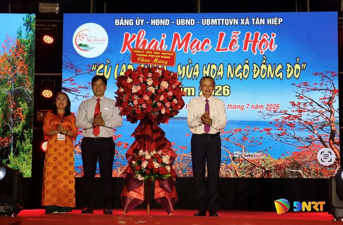 Phó Chủ tịch HĐND thành phố Đoàn Ngọc Hùng Anh (bên phải) tặng hoa chúc mừng khai mạc lễ hội cho lãnh đạo xã Tân Hiệp. Ảnh: QUỐC TUẤN
