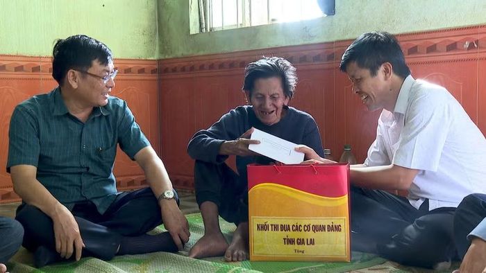  Đại diện khối thi đua các cơ quan Đảng tỉnh tặng quà cho thương binh Rơ Châm Khôi (ngồi giữa) ở làng Maih, xã Ia Hrung. Ảnh: Mạnh Hà 