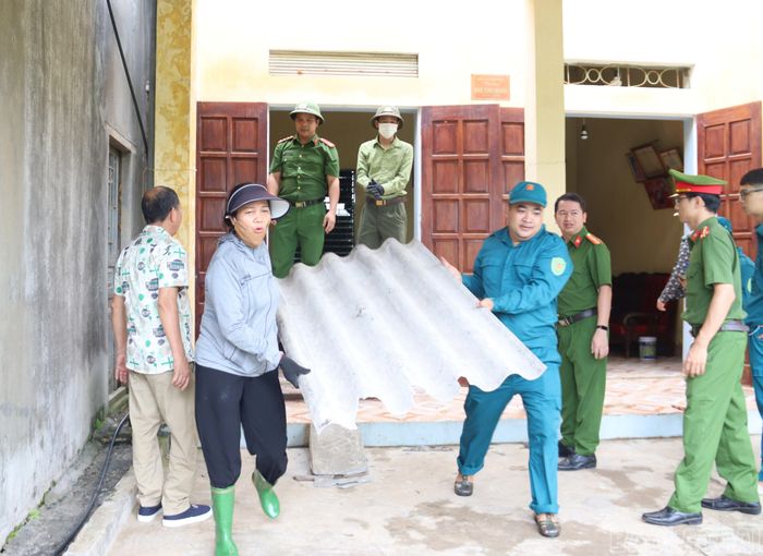 Lực lượng công an và dân quân phường hỗ trợ gia đình vận chuyển vật liệu.