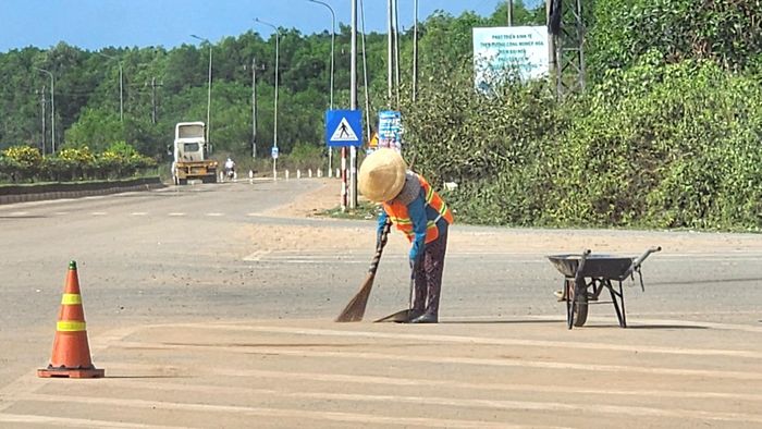 Tại vị trí nút giao QL24C dẫn về trung tâm xã Vạn Tường, để giảm bụi gây ô nhiễm, các đơn vị cử công nhân đến quét dọn, thu gom đất rơi vãi.