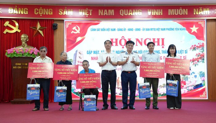 Đại diện Cảnh sát biển Việt Nam và phường Yên Nghĩa trao sổ tiết kiệm "Tình nghĩa" tới các gia đình người có công có hoàn cảnh khó khăn. Ảnh: PT