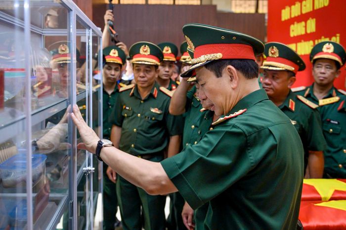 Đại tướng Phan Văn Giang quan sát các di vật được tìm thấy trong đợt quy tập hài cốt tại rãnh mộ A, nay được bảo quản thận trọng và cất trong tủ kính.