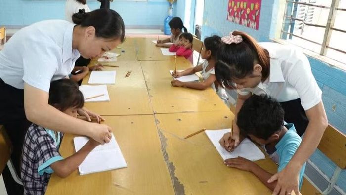 Giáo viên tại điểm trường Suối Hai, Trường tiểu học Cam Phước Đông 1, phường Ba Ngòi, tỉnh Khánh Hòa giúp các em học sinh dân tộc Raglai rèn chữ viết trên lớp học hè. (Ảnh: NGUYỄN TRUNG)