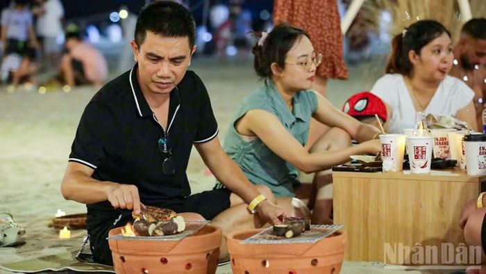 Du khách tự tay trải nghiệm nướng ngô, khoai tại bãi biển.